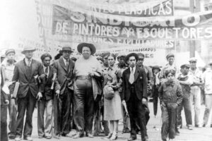 Above: Tina Modotti’s photograph of Frida Kahlo and Diego Rivera, with members of the Artists’ Union, on the May Day March, Mexico City, 1929 to protest for workers rights and to show working class unity.